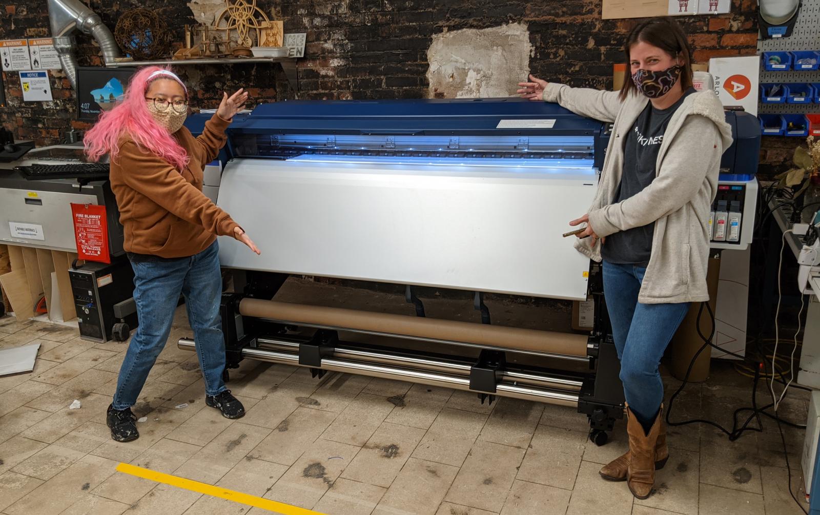 MakeHaven members Ruby and Kate display the new large format printer that arrived at MakeHaven in the fall of 2020