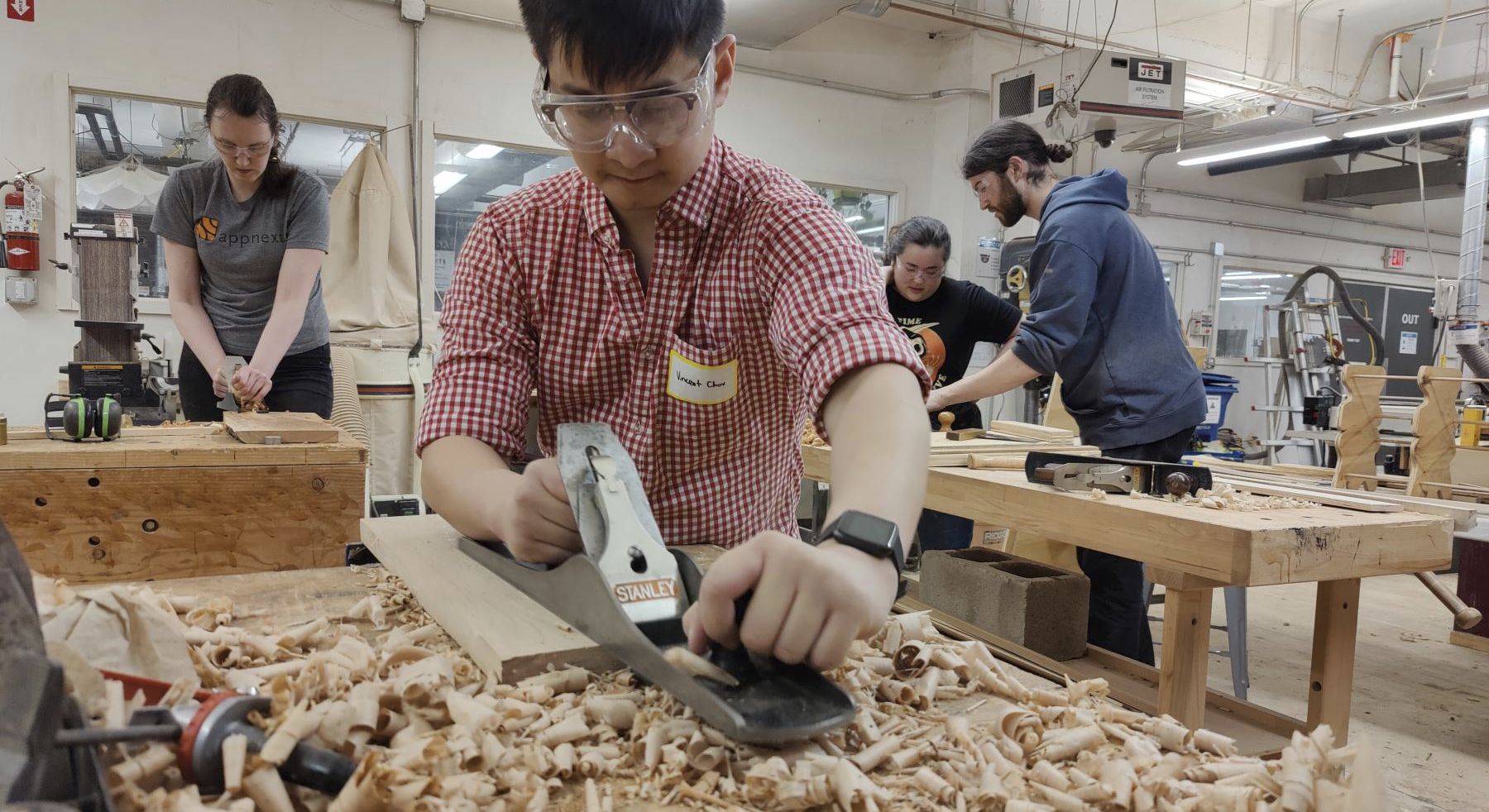 A MakeHaven member hand-planing a board in the woodshop
