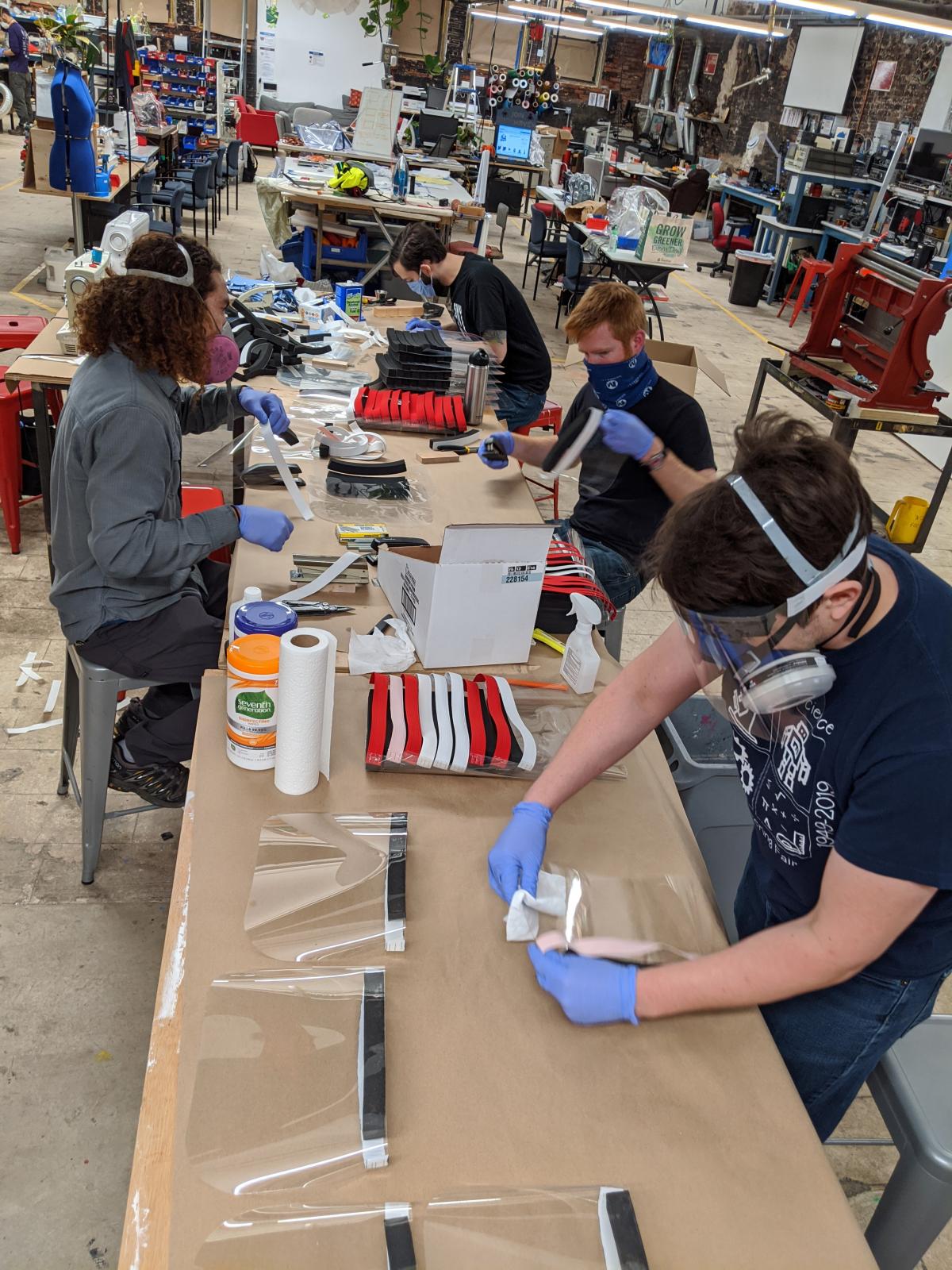 Socially distanced makers work in MakeHaven constructing face shields for essential workers.